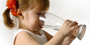 child girl drinking clean water from large glass