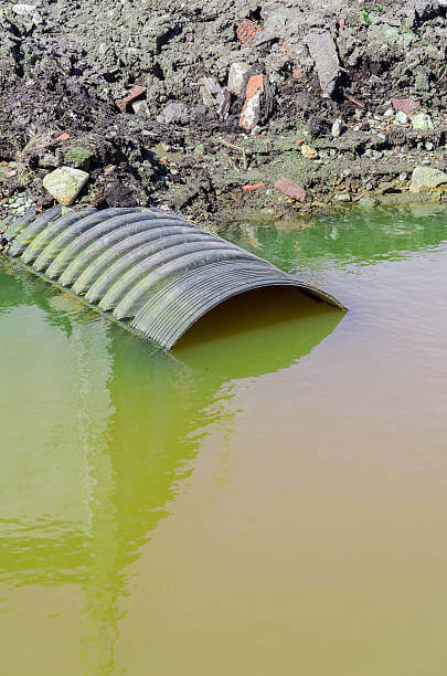 toxic green yellow water with half submerged exit pipe sewage and chemical drain