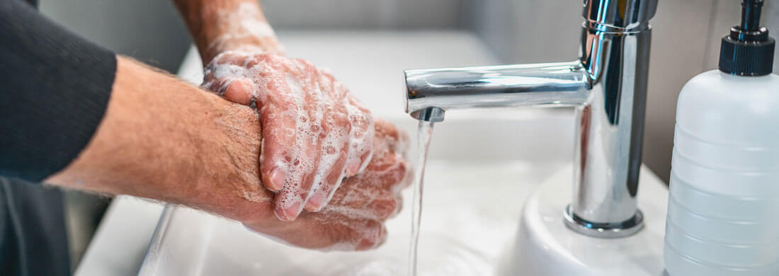man washing hands in bathroom sink rolles up sleeve soap chloramine titanium series